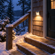 112-LED solar motion sensor wall light casting warm light on snow-lined cabin steps in Vermont at blue hour.