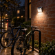 112-LED solar motion sensor wall light illuminating a wet bicycle parking area on a rainy night in Washington.