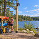 Unlit solar floodlight aimed toward a Michigan kayak equipment area, with a continuous clipped cable connecting the separate panel to the lamp.