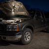 Magnetic rechargeable camping lantern attached under a pickup truck hood to illuminate the engine bay at night