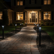 Luces solares de camino iluminando una zona exterior ajardinada por la noche