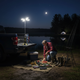 Linterna de camping recargable iluminando un equipo de pesca nocturna junto al agua