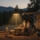 Linterna de camping recargable iluminando de noche un campamento familiar con tienda y zona de asientos exterior