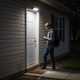 Luz solar de pared con sensor de movimiento iluminando una entrada lateral de casa por la noche