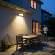 Luz solar de pared con sensor de movimiento iluminando un patio trasero residencial al anochecer