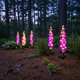 Solar delphinium flower lights illuminating a woodland-style garden at dusk