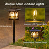 House-shaped solar garden light illuminated at night with warm light shining through its window-style openings