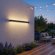 Aplique LED exterior largo iluminando al anochecer un patio trasero residencial