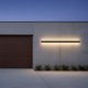 Aplique LED exterior largo iluminando de noche el exterior de un garaje residencial