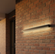 Aplique LED exterior largo iluminando el porche de una casa suburbana al anochecer