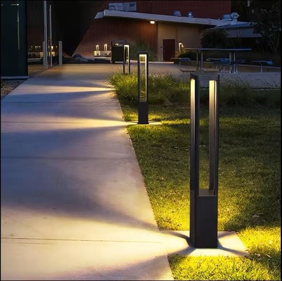 Modern black LED bollard light illuminated at night with controlled downward light for pathways and garden borders