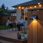Solar fence lights illuminating a modern patio alongside decorative string lights at dusk