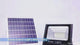 Outdoor solar LED floodlight with separate panel and remote shown in nighttime use