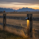 Luces solares para cercas instaladas a lo largo de una cerca estilo rancho al atardecer