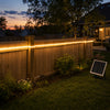 Warm-white solar COB LED strip installed along a low wooden fence in an American backyard at dusk