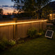 Tira LED COB solar blanco cálido instalada a lo largo de una cerca baja de madera en un patio estadounidense al anochecer