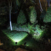 Solar landscape spotlights illuminating shrubs, trees and lawn at night with broad and focused beams in a garden setting