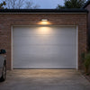 Solar motion sensor wall light illuminating a residential garage door and driveway at night