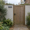 Solar motion sensor wall light mounted beside a wooden garden gate for outdoor entrance lighting