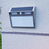 Aplique solar con sensor de movimiento iluminando de noche una zona exterior en entradas, garajes, patios y jardines traseros
