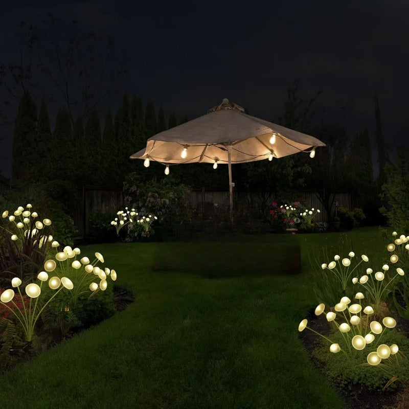 Solar mushroom and jellyfish garden stake lights glowing among plants in a yard at night