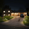 Solar mushroom stake lights lining the driveway of a ranch-style home at night