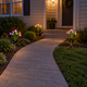 Warm white and RGB solar mushroom lights lining a front entrance walkway at dusk.