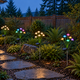 Warm white and RGB solar mushroom stake lights beside a stone path and cedar home in a Pacific Northwest-style garden.