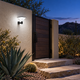 Solar radar wall light casting cool white light on a stucco courtyard wall beside desert landscaping and stone steps
