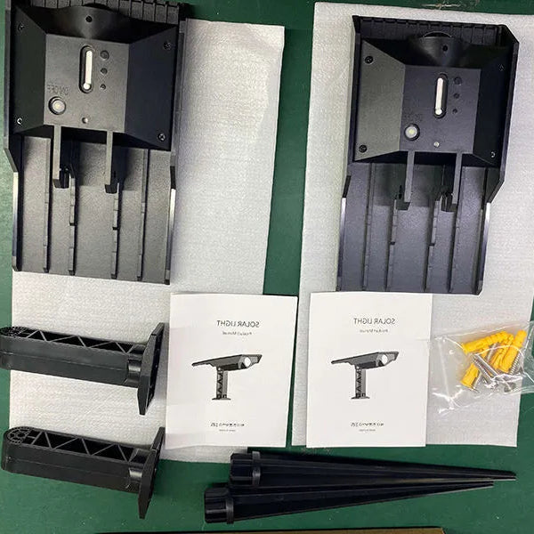 Two-pack solar tree light set with lights, ground stakes, instruction manuals and mounting hardware arranged in protective packaging