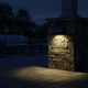 Luz solar para cerca iluminando de noche una columna de piedra en un patio