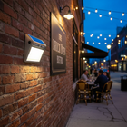 Solar motion sensor wall light illuminating the exterior of an urban restaurant at night
